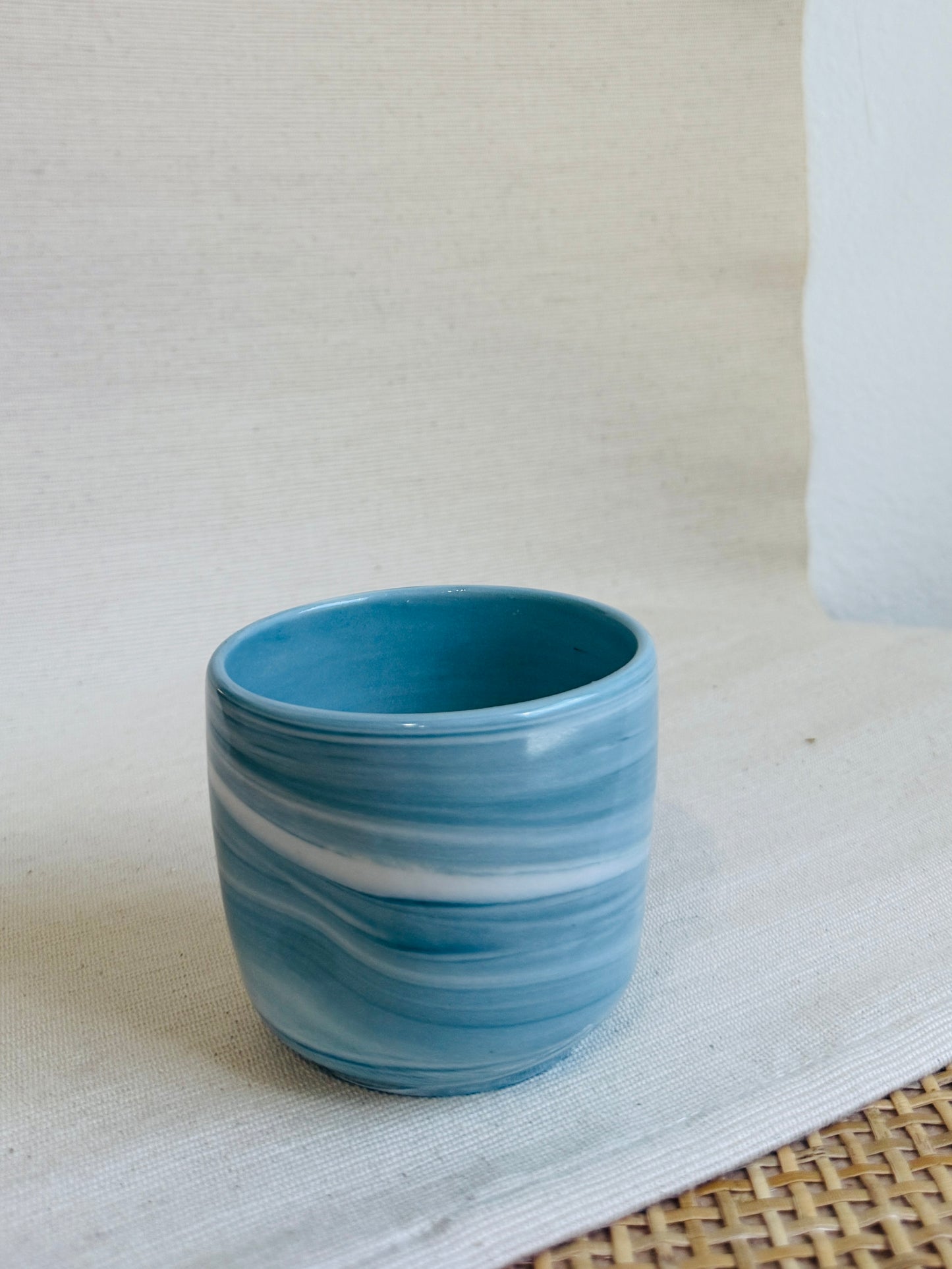 Blue ceramic cup with white swirl patterns on a light background