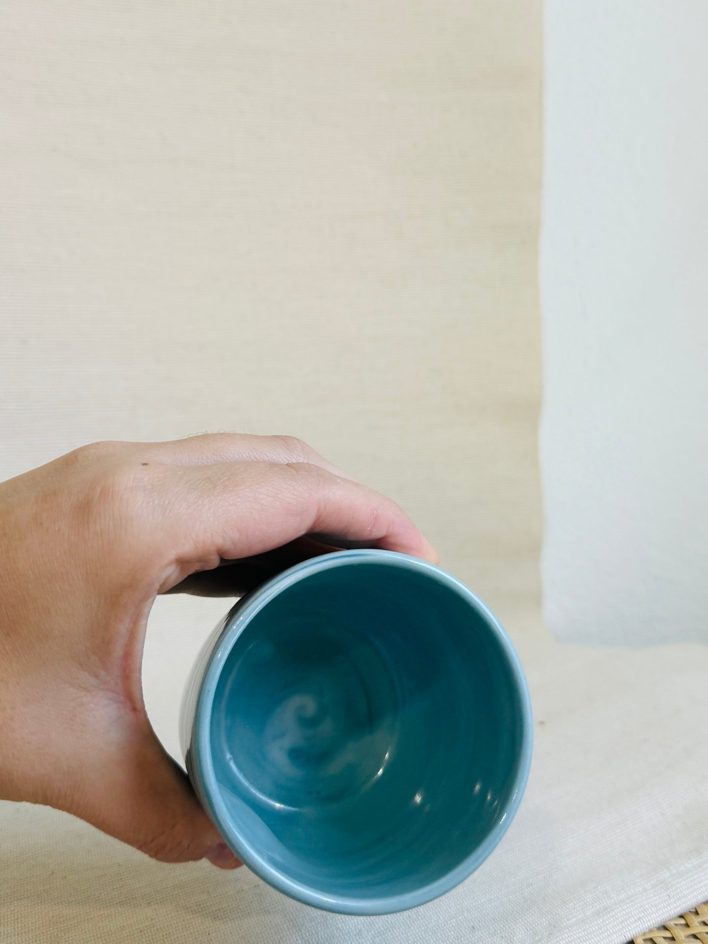 Hand holding a blue mug against a neutral background
