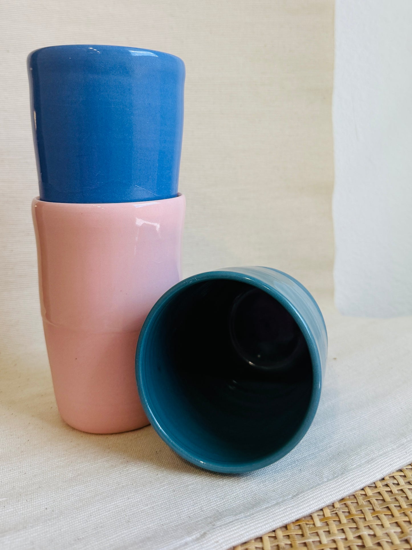 Three ceramic cups with blue and pink color scheme on a light background