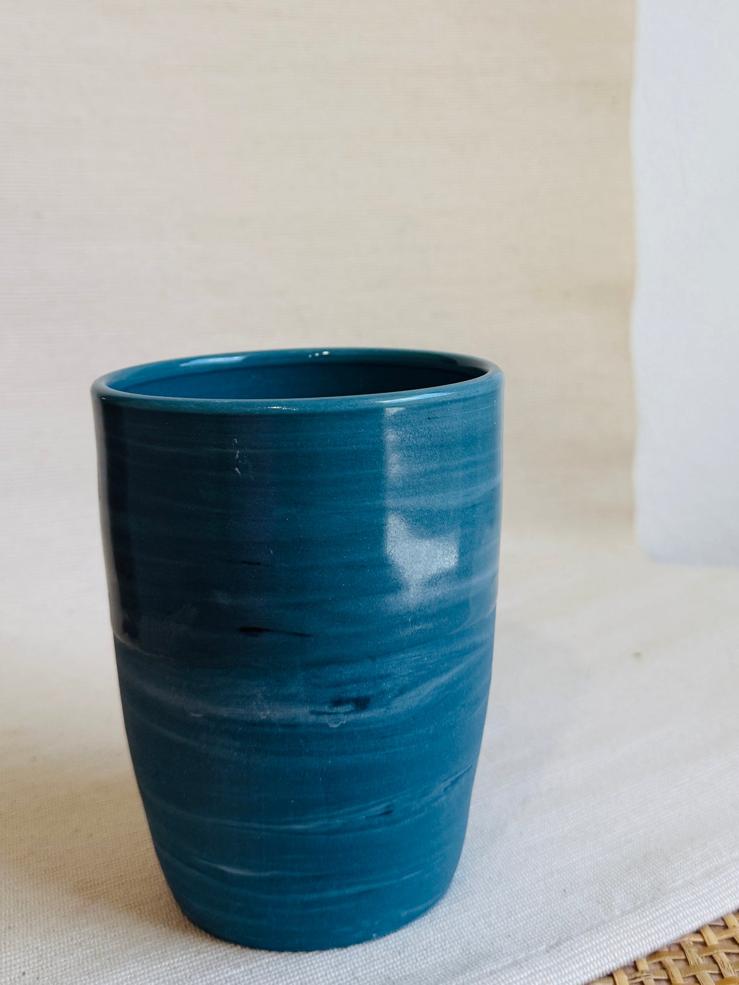 Teal ceramic tumbler on a light background