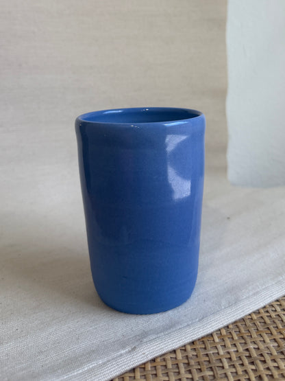 Blue ceramic cup on a textured surface with a neutral background