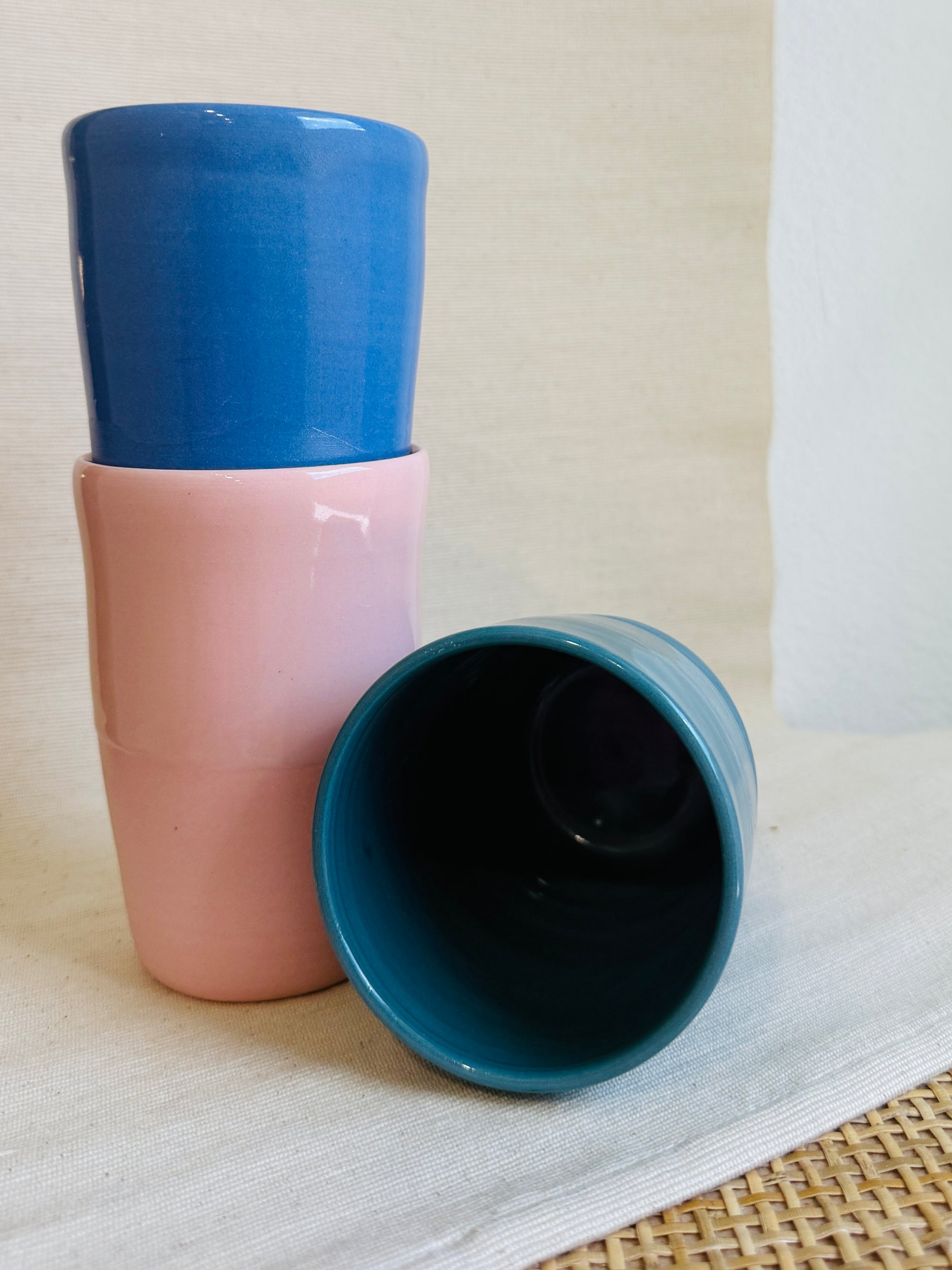 Three ceramic cups with blue and pink color scheme on a light background