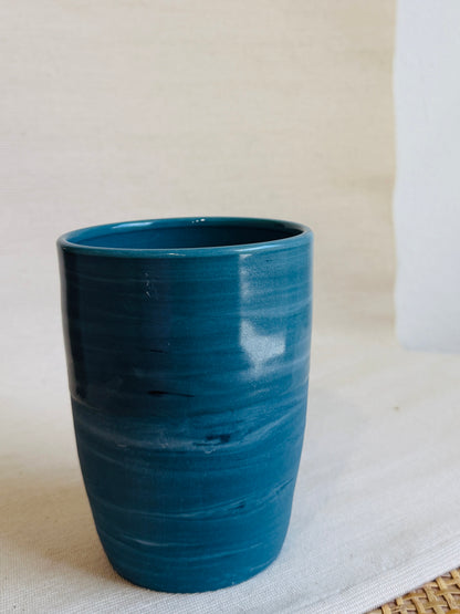 Teal ceramic tumbler on a light background